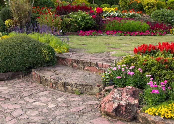 Jardin aménagé avec allée en pierre et massifs fleuris